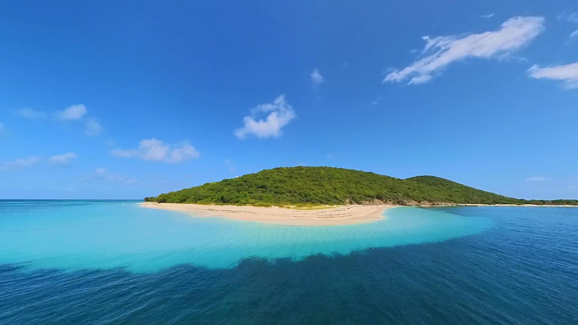 Buck Island's green hill and white-sand point from the water